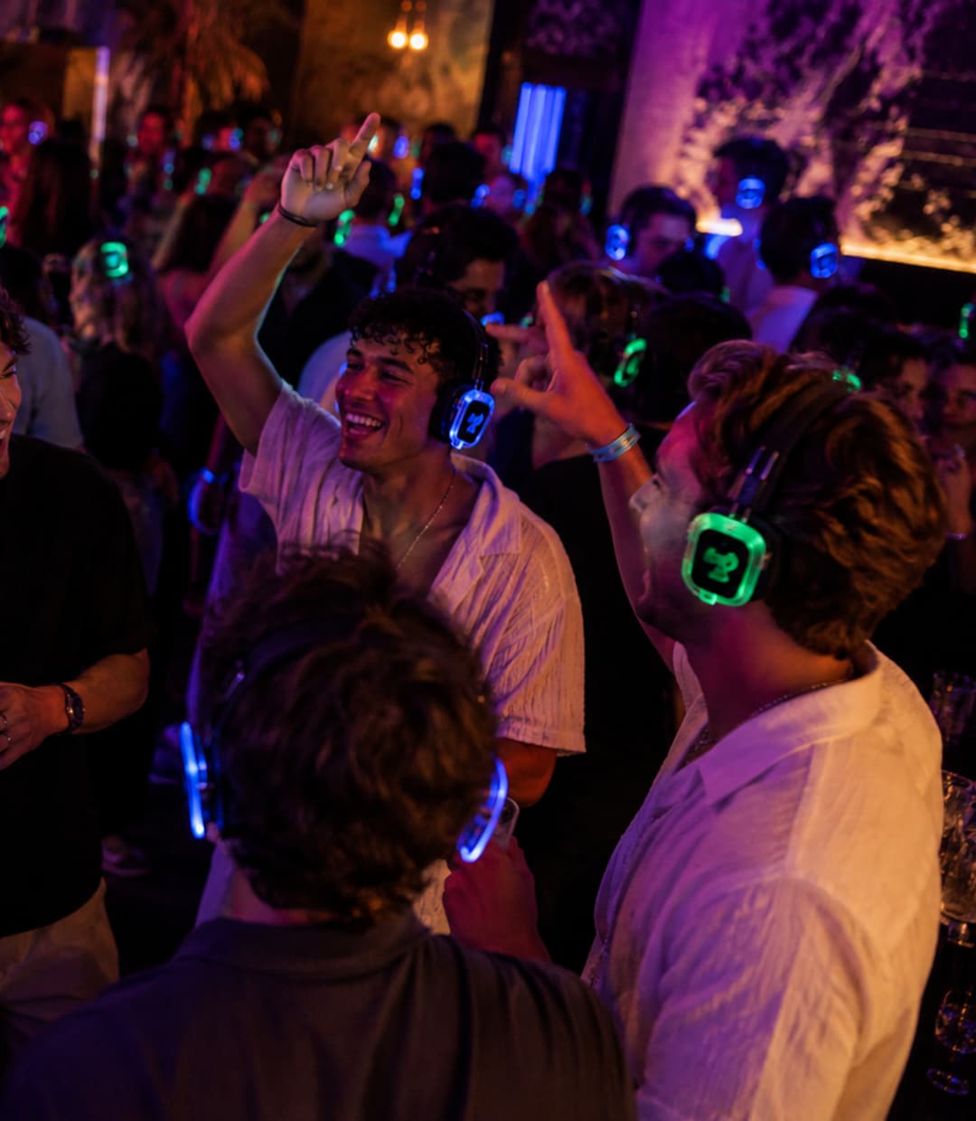 Een groep gasten danst en zingt mee, de koptelefoons lichten blauw op